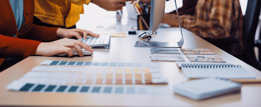 A vibrant workspace shows creative professionals actively collaborating, sharing color samples, and engaging in a productive design process at a modern office desk setup. SACTR - Powered by Adobe