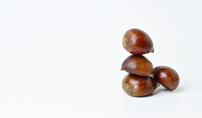 Obraz premium Chestnuts stacked on a white background. Close up and copy space.