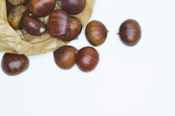 Chestnuts on a white background and paper bag,  zenith view.