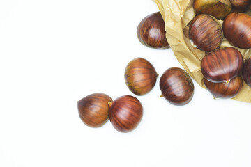 Close up of chestnuts on a white background and paper bag,  zenith view.