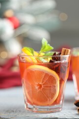 Tasty punch drink in glass on white wooden table against background with blurred lights, closeup. Bokeh effect