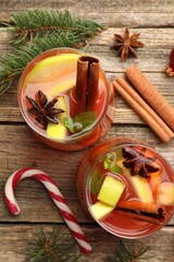 Tasty punch drink in glasses, spices and Christmas decor on wooden table, flat lay