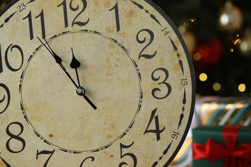 Wall clock against dark background with blurred lights, closeup. New Year greeting card