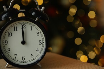 Alarm clock on wooden table against dark background with blurred lights, closeup with space for...