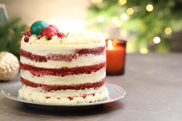 Delicious sponge cake with Christmas decor and red currants on grey textured table against blurred lights, closeup with space for text. Bokeh effect