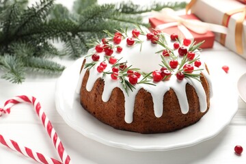 Tasty Christmas cake with icing, cranberries and rosemary on white wooden table, closeup