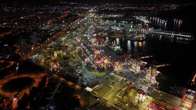 Illuminated mersin port at night with container ships, gantry cranes and busy cargo terminals against a glowing cityscape, highlighting global shipping and logistics