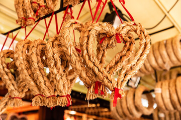 Décorations de Noël traditionnelles en forme de coeur en paille tressée, suspendues sur un stand de marché de Noël en Alsace, style nordique et scandinave