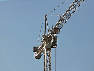 Naklejka premium Tower cranes work during the construction of a multi-story building. New apartments for residents and premises for offices. Risky work at height. Lifting heavy building materials. City development