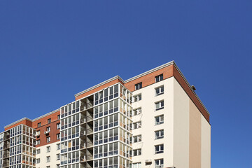 Fototapeta premium Lviv, Ukraine - 3 4 2020: Facade of a tall multi-storey modern house with balconies and large glass windows. Design of modern architecture. Top view from the bottom. Modern city architecture