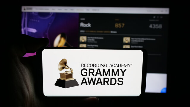 Stuttgart, Germany - 10-31-2025: Person holding cellphone with logo of US music award Grammy Awards (The Grammys) on screen in front of webpage. Focus on phone display.