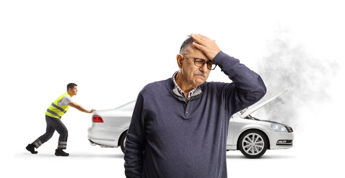 Upset man holding his head and roadside assistance worker pushing his car