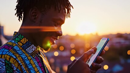 A man holds a smartphone, looking at the screen while standing against a beautiful sunset backdrop. The vibrant colors of the sunset create a serene atmosphere for the man. - Powered by Adobe