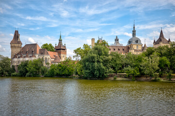 Fototapeta premium Budapest, Hungary - July 27, 2025: Vajdahunyad Castle reflected in the lake of City Park, showcasing its mix of Gothic, Romanesque, Renaissance, and Baroque architectural styles 