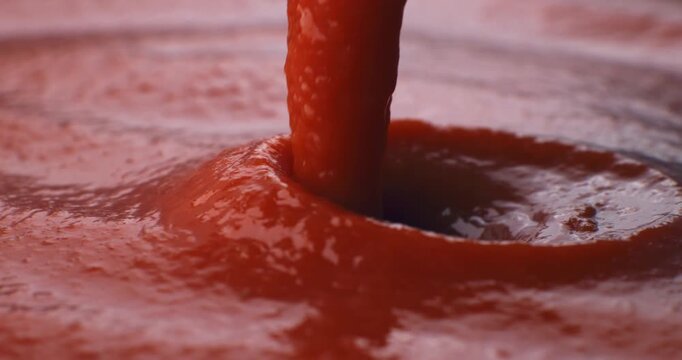 Slow motion macro of thick vibrant tomato sauce pouring showing smooth texture and deep red tones under natural lighting. at 1000 fps. Concept of freshness, tradition and Italian cooking art. 