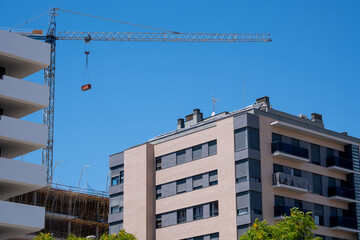 Urban construction scene with crane and modern apartment buildings against clear blue sky