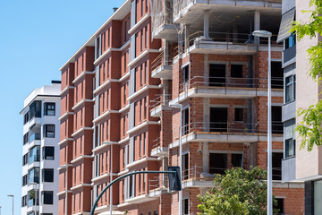 Fototapeta premium Modern urban architecture featuring new brick apartment buildings under construction