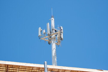 Cellular communication tower against clear blue sky on rooftop