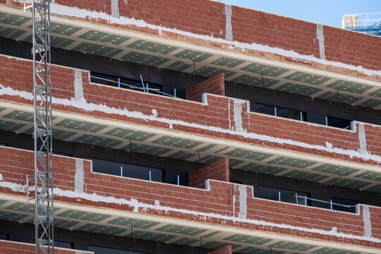 Modern building construction with bricks and concrete elements against a clear blue sky