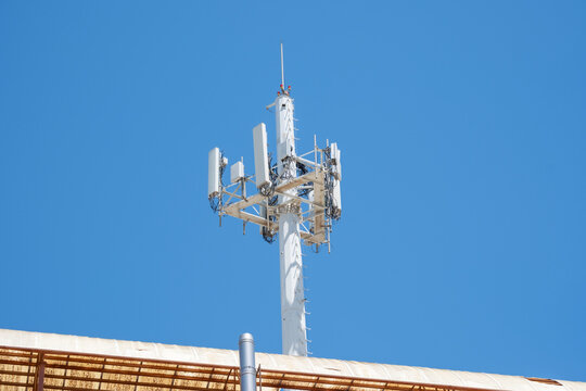 Cellular communication tower against clear blue sky on rooftop