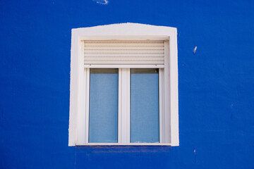 Minimalist white window on vibrant blue wall in mediterranean style architecture