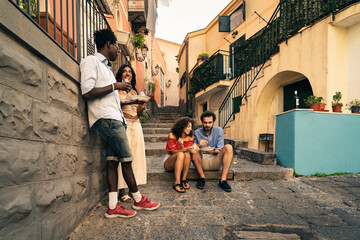 Friends enjoy a lively moment on a charming street in an Italian village during a sunny afternoon