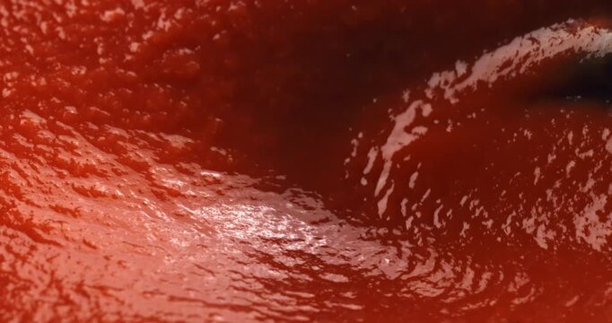 Slow motion macro of thick vibrant tomato sauce swirling showing smooth texture and deep red tones under natural lighting. at 1000 fps. Concept of freshness, tradition and Italian cooking art. 