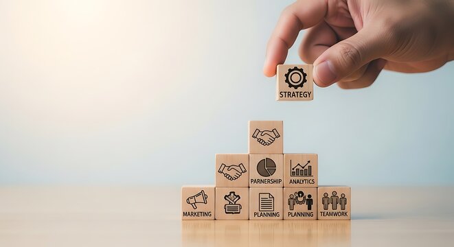 Hand placing a wooden block with strategy icon on a pyramid of business concept blocks