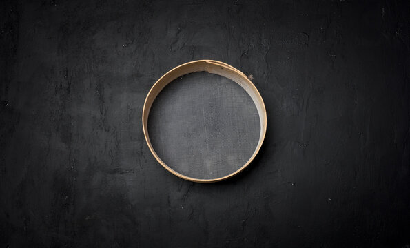 A round kitchen strainer with a wooden rim and fine mesh