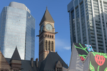Fototapeta premium almost half-pas three on the clock and bell tower of Old City Hall, contrasted with modern office and retail buildings, seen from Nathan Phillips Square, Toronto