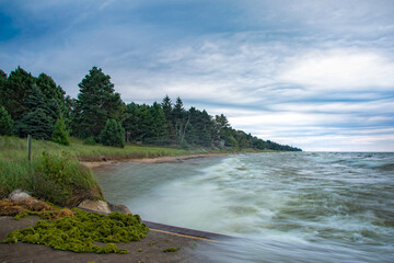 Waves crash against the shore near Cave Point along Lake Michigan on a cloudy day