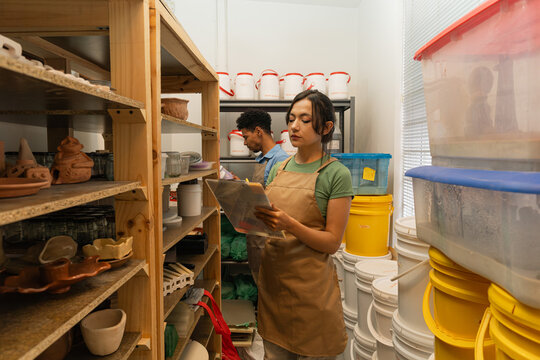 Entrepreneurs managing inventory in pottery workshop - Powered by Adobe