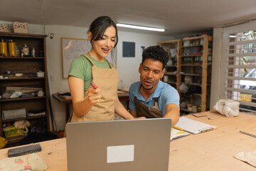 Latin American entrepreneurs working together on laptop in workshop