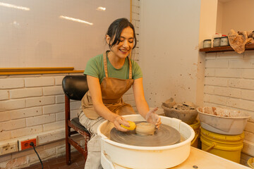 Young woman enjoying pottery class shaping clay on wheel