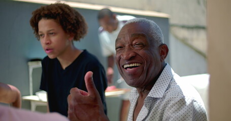 African American senior showing a thumbs-up gesture during a family meal outdoors, expressing joy and positivity in a vibrant  gathering and connection