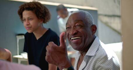 African American senior showing a thumbs-up gesture during a family meal outdoors, expressing joy and positivity in a vibrant  gathering and connection