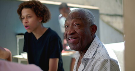 African American senior showing a thumbs-up gesture during a family meal outdoors, expressing joy...