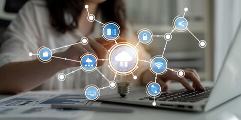 A business professional engages in digital tasks on a laptop, surrounded by cloud technology symbols, showcasing innovation and data-driven strategies in a modern office environment. Crux