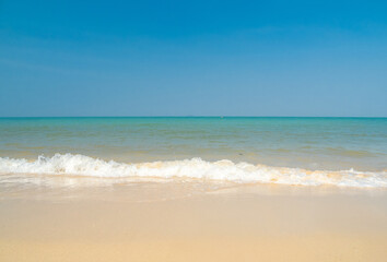 Peaceful panorama tropical sea beach with gentle waves rolling onto golden sand under bright blue sky with fluffy white clouds. relaxing summer scene perfect scene for travel holliday and nature lover