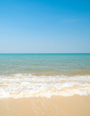 Peaceful tropical sea beach with gentle waves rolling onto golden sand under bright blue sky with fluffy white clouds. relaxing summer scene perfect scene for travel holliday and nature lovers