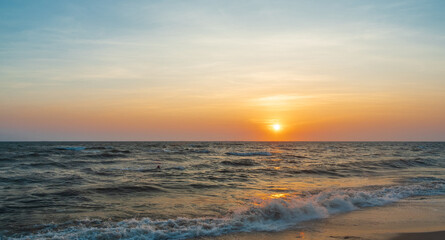 Obraz premium serene panorama image capture beauty sunset over calm ocean. sun low on horizon casting warm golden glow across sky and reflect off gentle wave. warm orange near creating peaceful calm atmosphere.