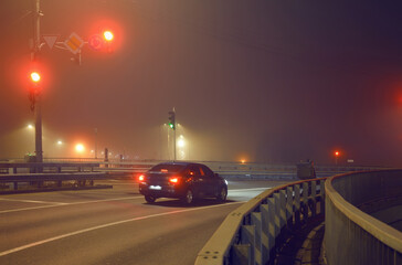 Lone car at a city intersection at night in foggy winter weather
