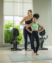 Obraz premium mother and daughter lying on exercise mats in a home gym, smiling while looking at a laptop screen. The scene highlights family bonding, fitness, and the use of technology for home workouts.
