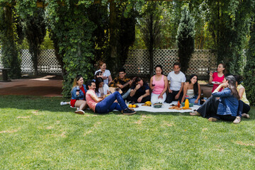 Big latin family sitting on picnic blanket in park during weekend Sunday sunny day in Mexico Latin...