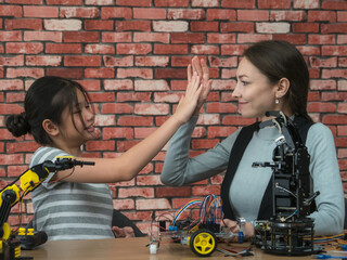 Teacher and student two person diverse individuals collaborating on robotics project in modern workspace. assembling and programming robotic arms, showcasing teamwork, innovation, and STEM education.