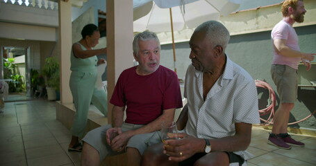 Two elderly friends sitting and conversing at a backyard barbecue, sharing meaningful dialogue and...