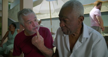 Two elderly friends sitting and conversing at a backyard barbecue, sharing meaningful dialogue and connection during a relaxed and casual outdoor gathering