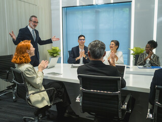 man present plan work to group businessprofessional engaged meeting discuss data display multiple screen show chart graph, use tablet while other seated around conference table with laptop