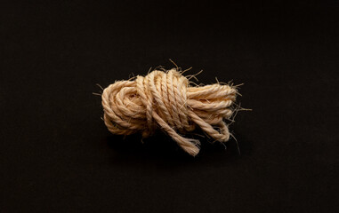 Coiled hemp rope tied in a knot on black background symbolizing strength