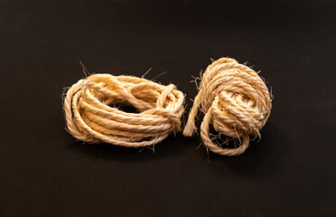 Two coiled natural fiber ropes on dark black background close up